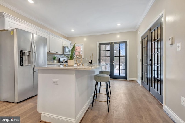 kitchen with white cabinetry, french doors, a kitchen island, and stainless steel appliances