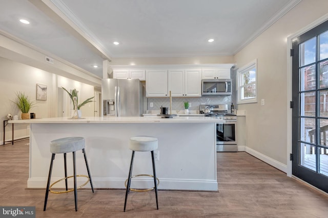 kitchen featuring a kitchen island with sink, a breakfast bar area, light wood-type flooring, white cabinetry, and stainless steel appliances