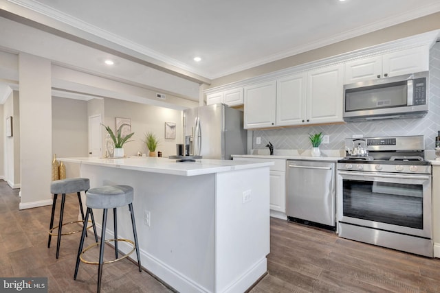 kitchen with white cabinets, appliances with stainless steel finishes, a center island, and decorative backsplash