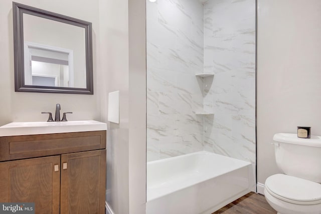 full bathroom with vanity, hardwood / wood-style floors, tiled shower / bath combo, and toilet