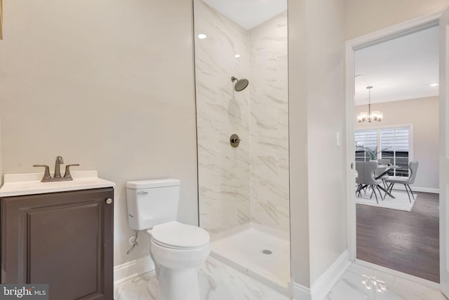 bathroom featuring tiled shower, vanity, toilet, and a notable chandelier