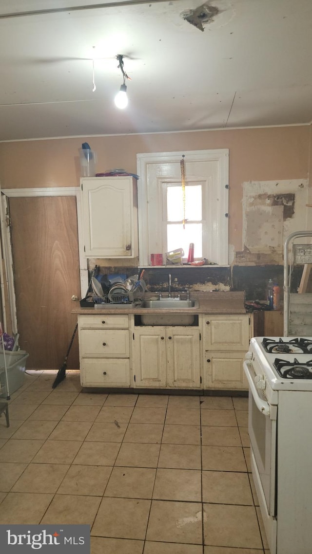 kitchen with white range, light tile patterned floors, and sink