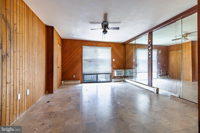 unfurnished room featuring ceiling fan, a baseboard heating unit, and wood walls