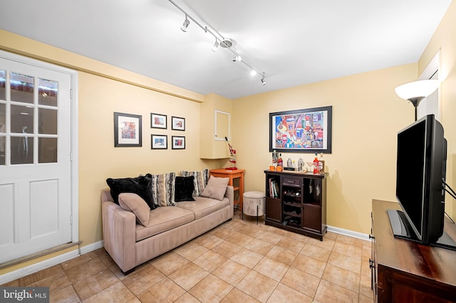 living room featuring baseboards, rail lighting, and light tile patterned flooring