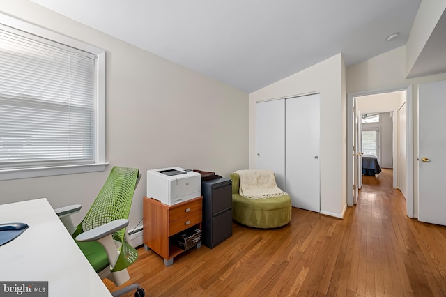 office with light wood-style floors, a baseboard radiator, and vaulted ceiling
