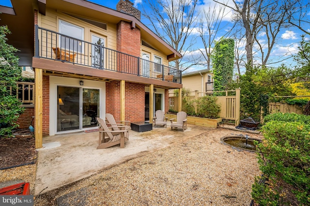 back of house featuring fence, a patio area, brick siding, and a chimney