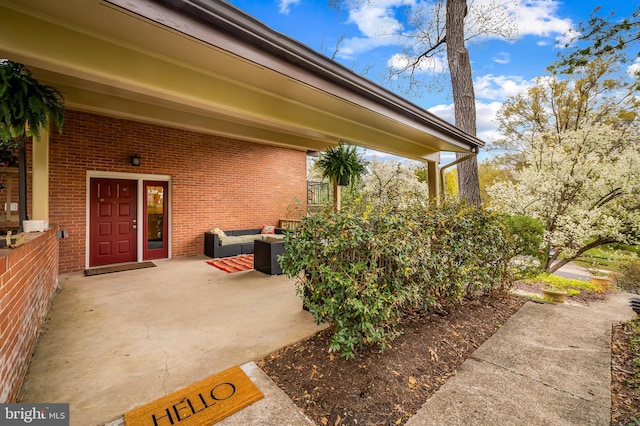 doorway to property featuring a patio, an outdoor hangout area, and brick siding