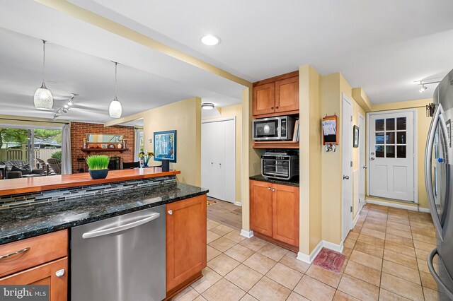 kitchen featuring track lighting, hanging light fixtures, light tile patterned floors, brown cabinets, and stainless steel appliances