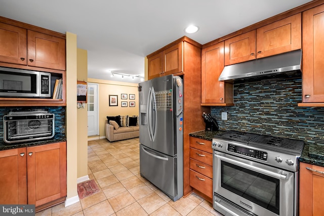 kitchen featuring tasteful backsplash, light tile patterned flooring, under cabinet range hood, brown cabinets, and stainless steel appliances