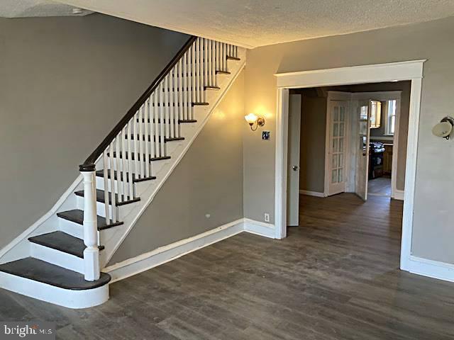 stairway with wood-type flooring and a textured ceiling