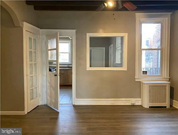 spare room featuring ceiling fan, radiator heating unit, and dark wood-type flooring