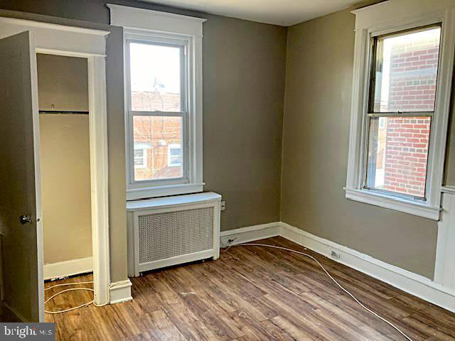 unfurnished bedroom featuring radiator and hardwood / wood-style flooring