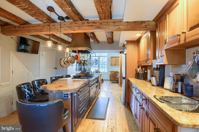 kitchen featuring beam ceiling, a center island, light hardwood / wood-style flooring, ventilation hood, and decorative light fixtures