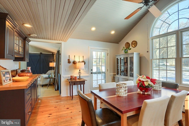 dining room with a barn door, wood ceiling, lofted ceiling, and light wood-type flooring