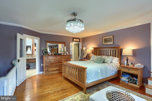 bedroom featuring light wood-type flooring, crown molding, connected bathroom, and an inviting chandelier