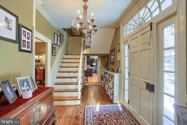 foyer entrance featuring light hardwood / wood-style floors, crown molding, and a chandelier