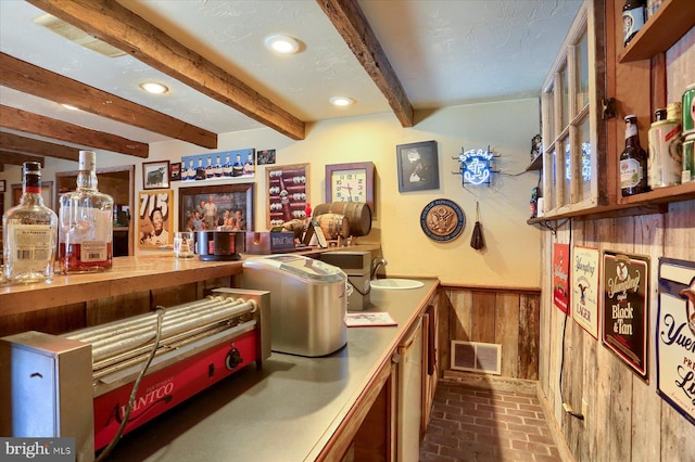 interior space featuring beamed ceiling, wooden walls, and sink