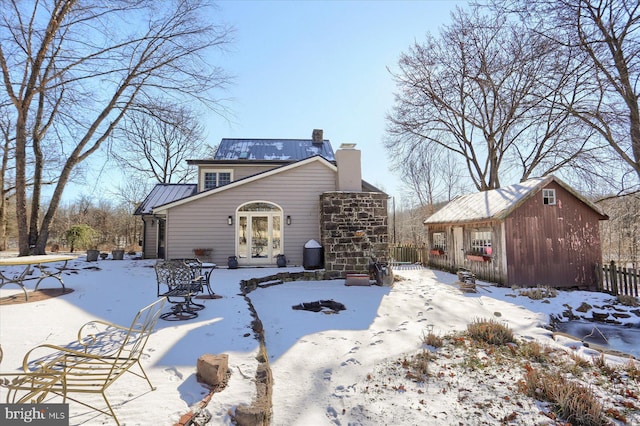 snow covered rear of property featuring an outbuilding