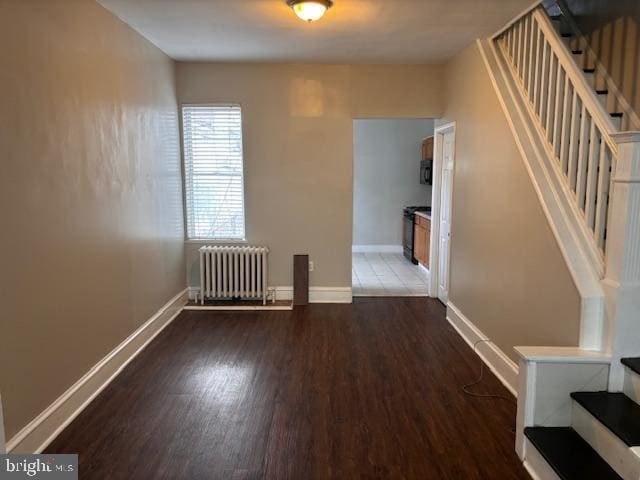 empty room featuring dark hardwood / wood-style floors and radiator heating unit