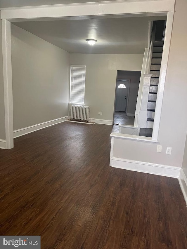 spare room featuring dark hardwood / wood-style flooring and radiator heating unit