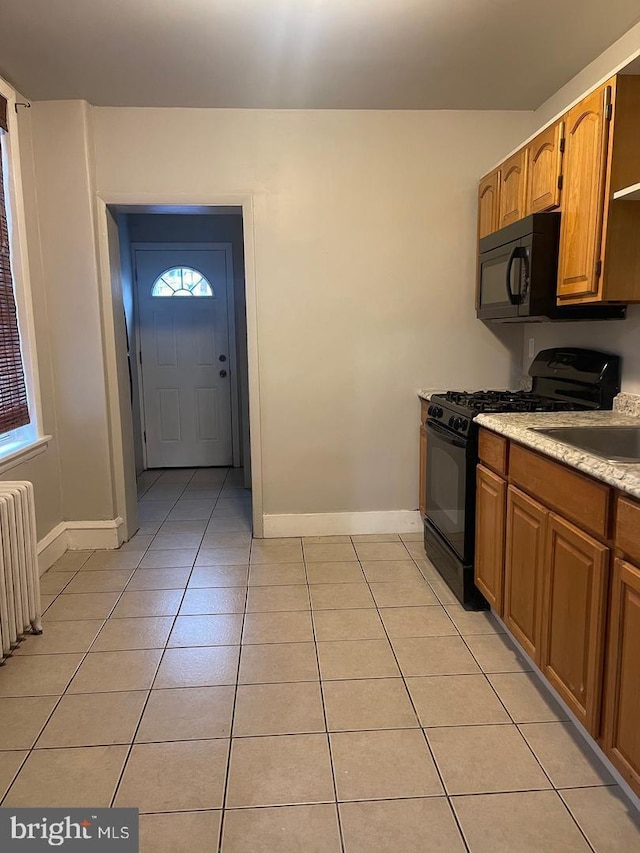 kitchen featuring light tile patterned floors, sink, radiator, and black appliances