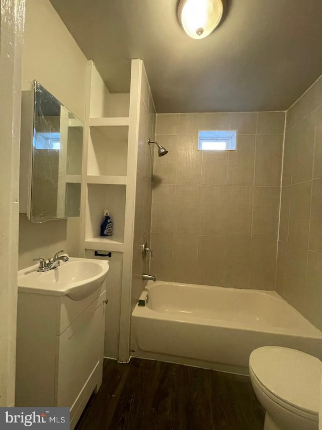 full bathroom featuring vanity, hardwood / wood-style floors, tiled shower / bath combo, and toilet