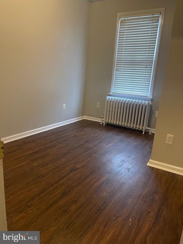 unfurnished room featuring radiator heating unit and dark wood-type flooring