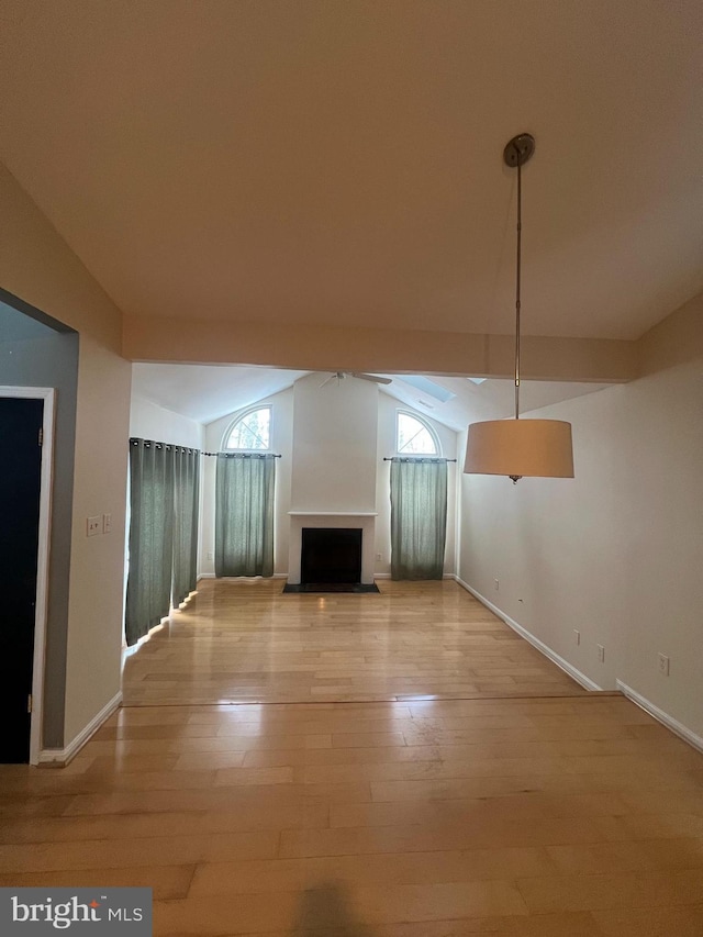 unfurnished living room featuring light wood-type flooring, a wealth of natural light, and vaulted ceiling