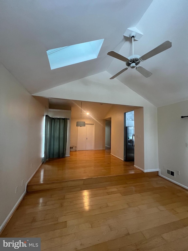 spare room featuring ceiling fan, light hardwood / wood-style flooring, and lofted ceiling with skylight