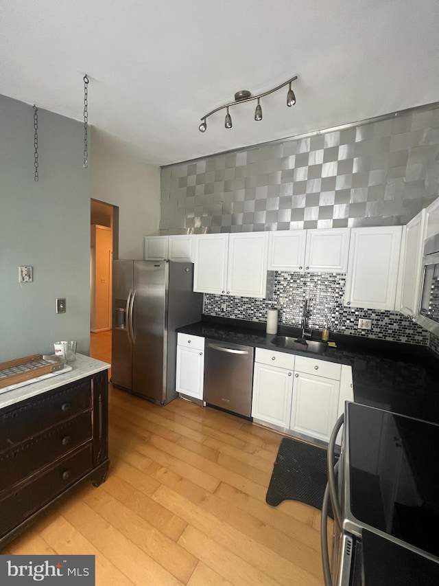 kitchen featuring white cabinetry, sink, stainless steel appliances, tasteful backsplash, and light hardwood / wood-style floors