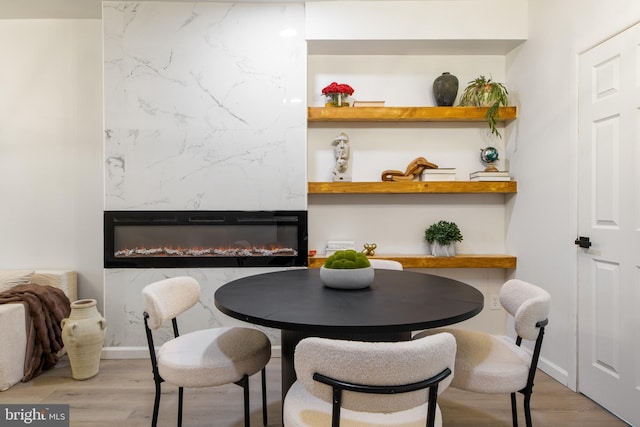 dining area featuring a large fireplace and wood-type flooring