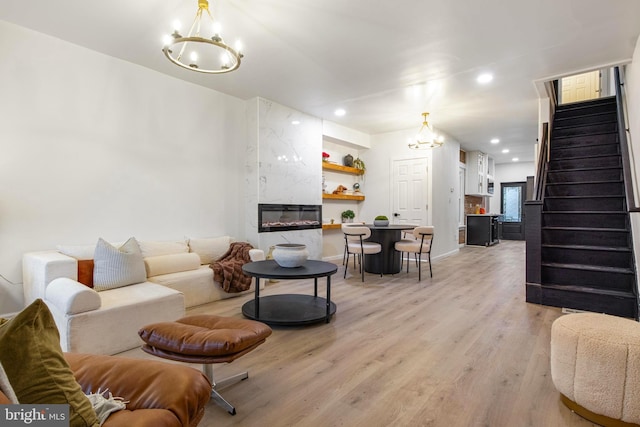 living room with a chandelier, a high end fireplace, and light hardwood / wood-style flooring