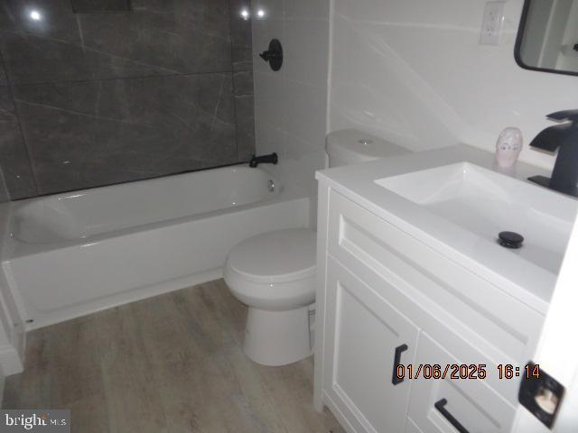 full bathroom featuring hardwood / wood-style floors, vanity, toilet, and tiled shower / bath