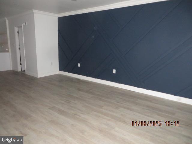 empty room with wood-type flooring and crown molding