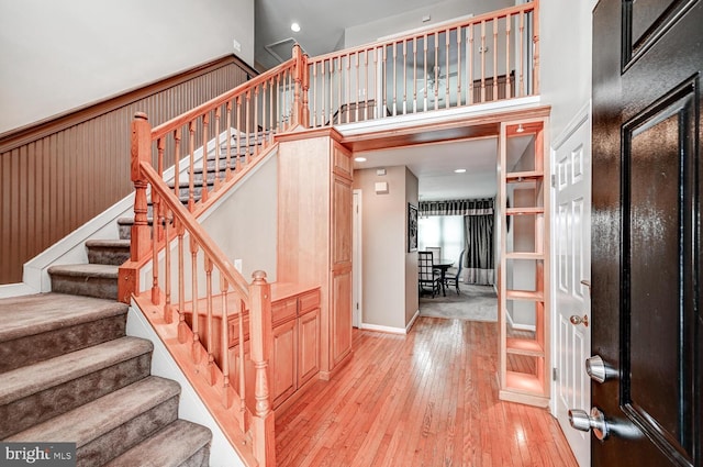 stairway with wood-type flooring and a high ceiling