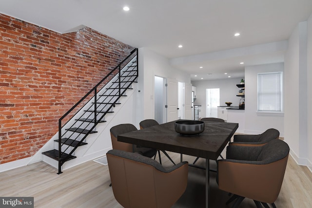 dining area with light hardwood / wood-style flooring and brick wall