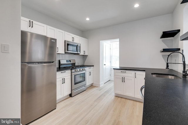 kitchen featuring white cabinets, light wood-type flooring, stainless steel appliances, and sink