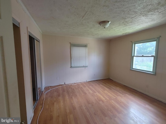 empty room with light hardwood / wood-style floors and a textured ceiling