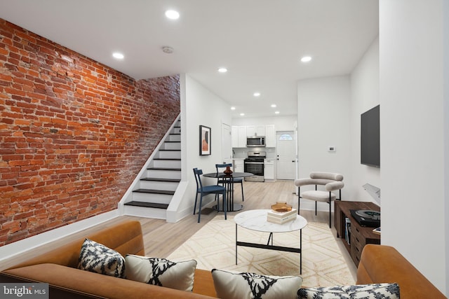 living room with light hardwood / wood-style floors and brick wall