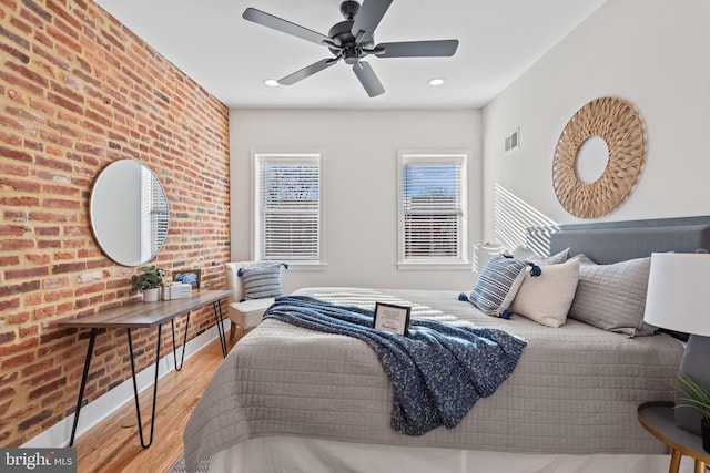 bedroom featuring ceiling fan, brick wall, and light hardwood / wood-style flooring