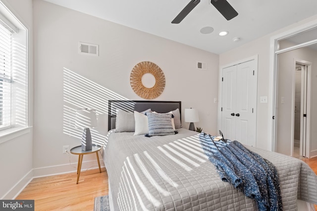 bedroom featuring multiple windows, a closet, ceiling fan, and hardwood / wood-style flooring