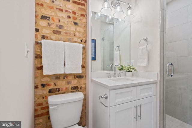 bathroom with vanity, toilet, a shower with door, and brick wall