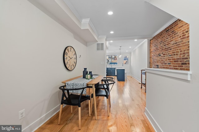 dining space with light wood-type flooring and ornamental molding