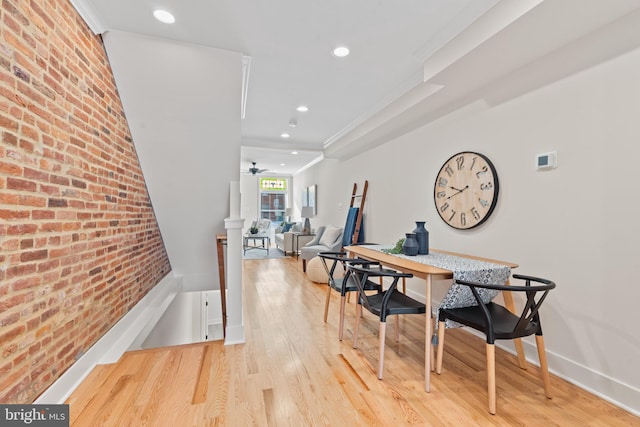 dining room featuring ceiling fan, hardwood / wood-style floors, brick wall, and ornamental molding