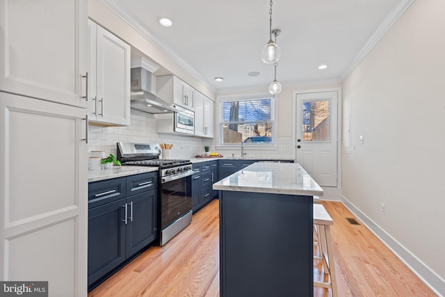 kitchen featuring appliances with stainless steel finishes, a kitchen island, blue cabinets, decorative light fixtures, and white cabinetry