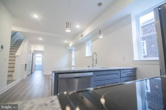 kitchen featuring gray cabinetry, sink, stainless steel dishwasher, hardwood / wood-style floors, and decorative light fixtures