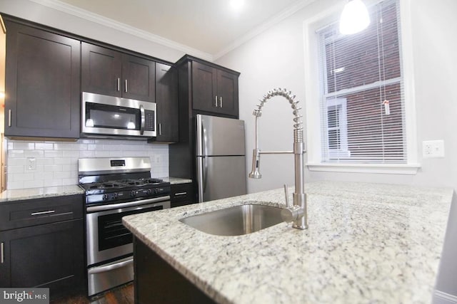 kitchen with sink, stainless steel appliances, tasteful backsplash, light stone counters, and crown molding