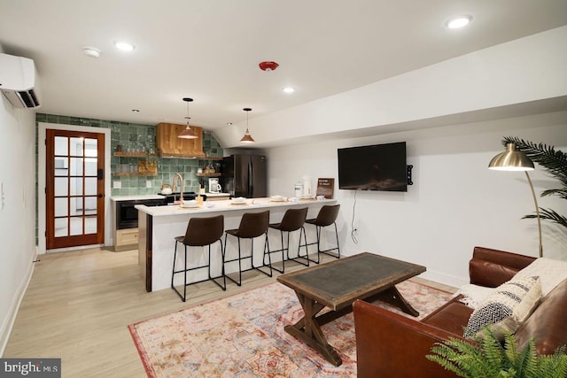 bar featuring black refrigerator, a wall mounted air conditioner, backsplash, pendant lighting, and light hardwood / wood-style flooring