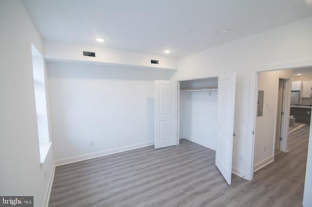 unfurnished bedroom featuring hardwood / wood-style floors, electric panel, and a closet