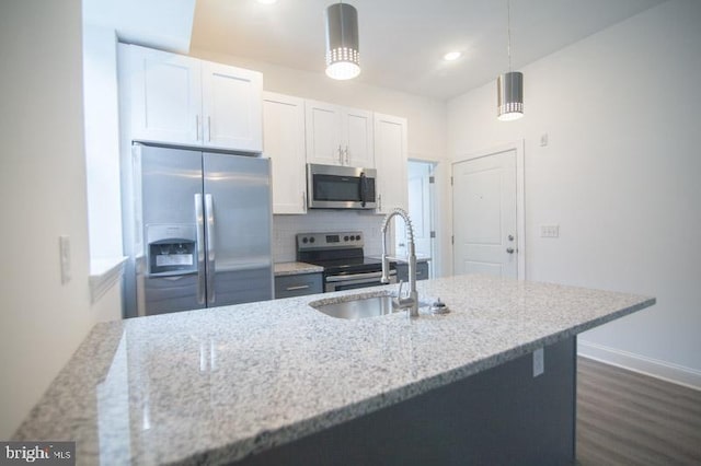 kitchen with light stone countertops, stainless steel appliances, white cabinets, and hanging light fixtures